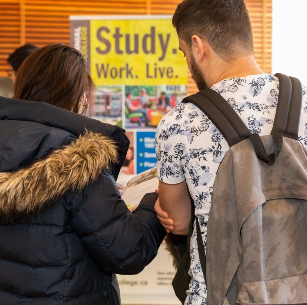 Students reading a brochure at ILAC Higher Education Fair