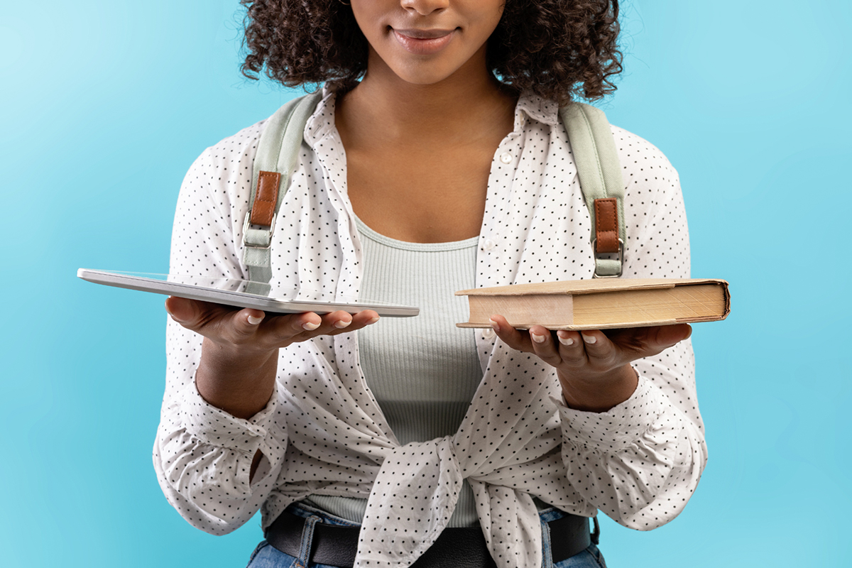 A person with a book in one hand and a tablet in the other