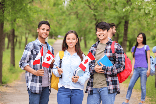 A group of students holding mini Canadian flags outdoors at one of the many Canadian universities in the country.