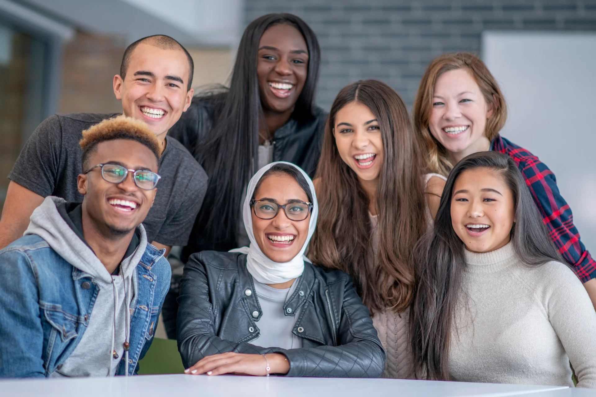 Seven young adults (of various races and ethnicities) post for a photo together.
