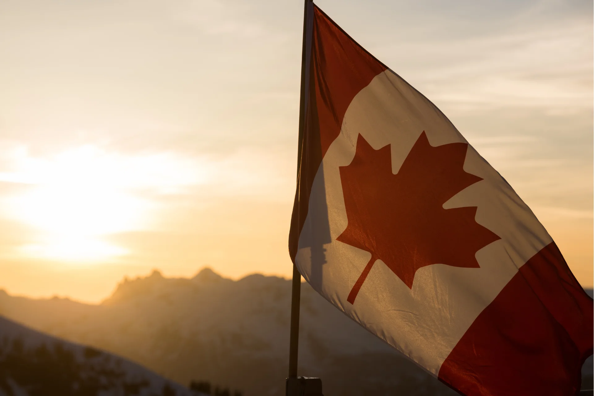 A Canadian flag is displayed with the sun setting behind it.