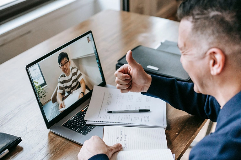  An English language tutor giving his tutee a thumbs up through a video call 
