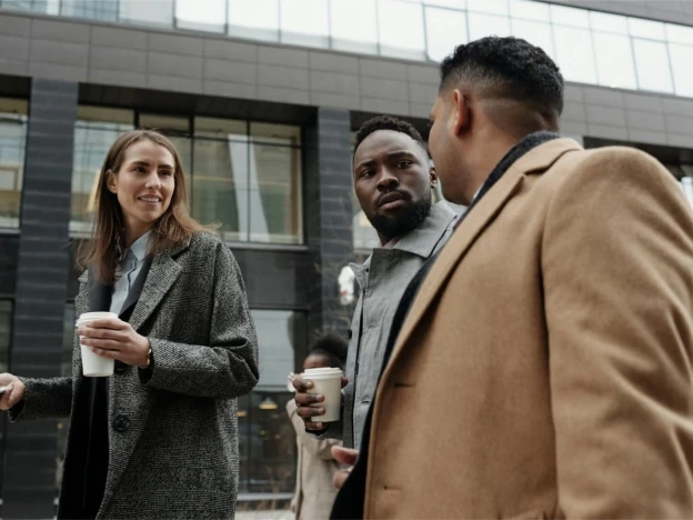 Three people in jackets talking to each other.