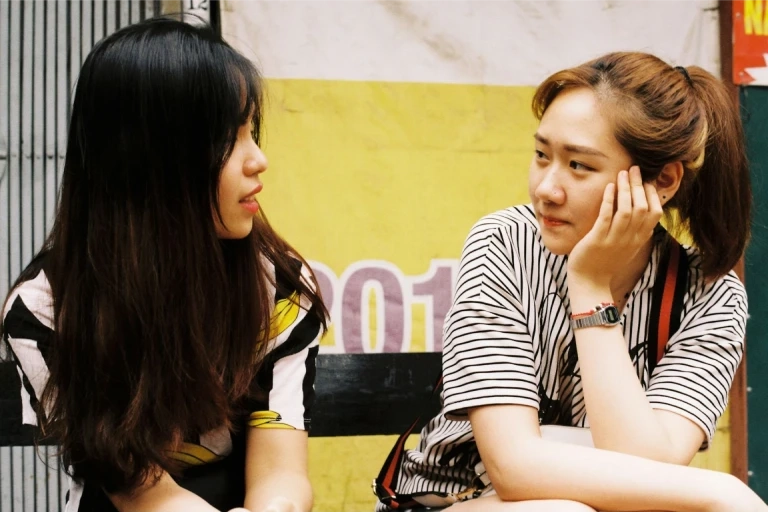 Two Asian women talking to each other intently.