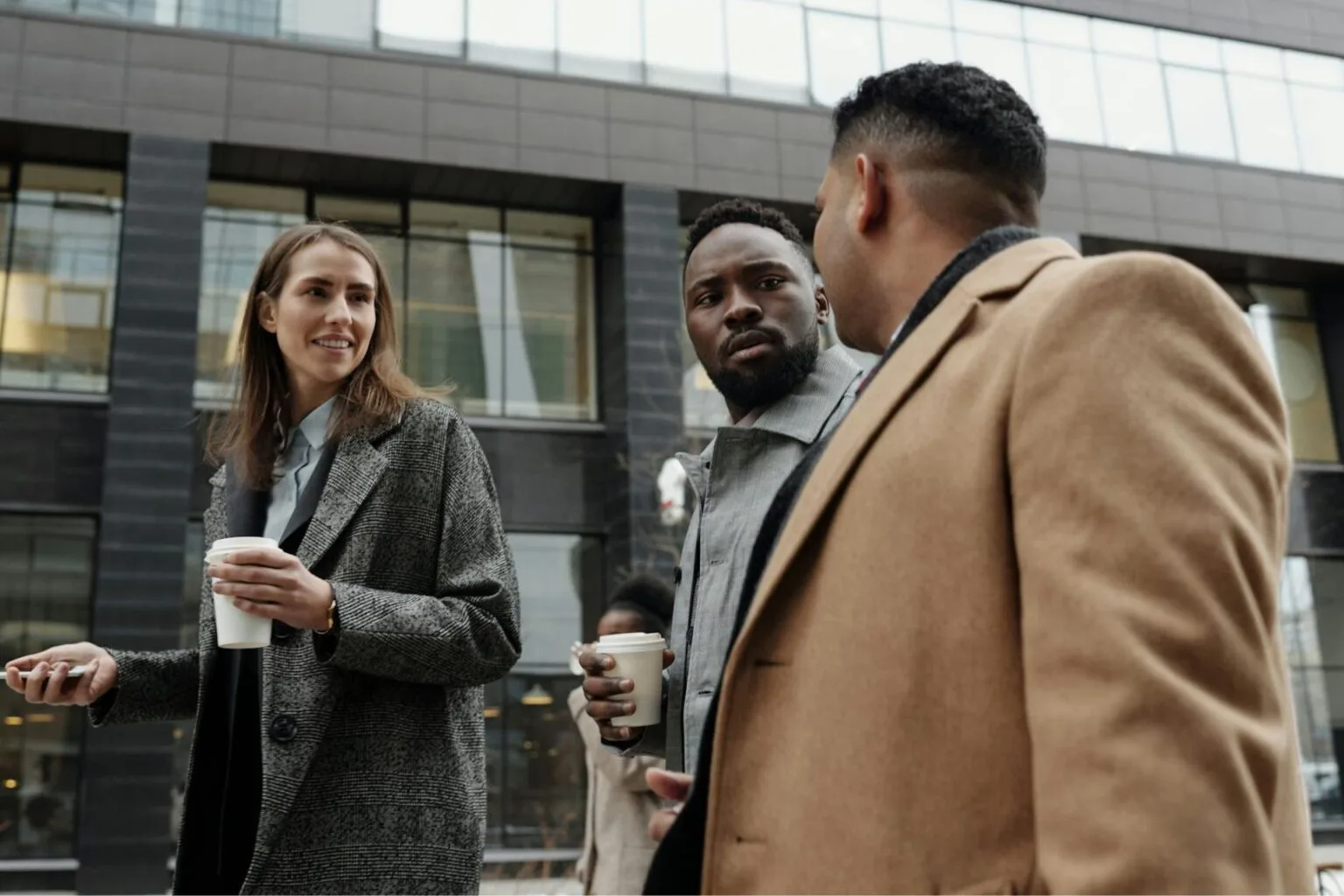 Three people in jackets talking to each other.