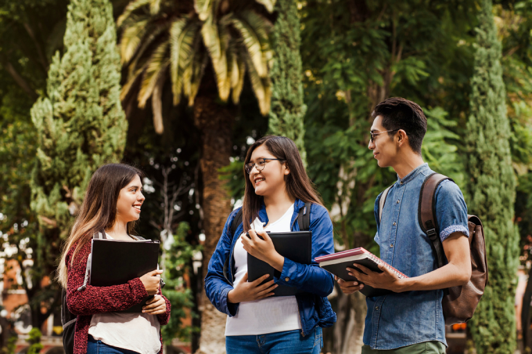 International students holding books and talking outdoors