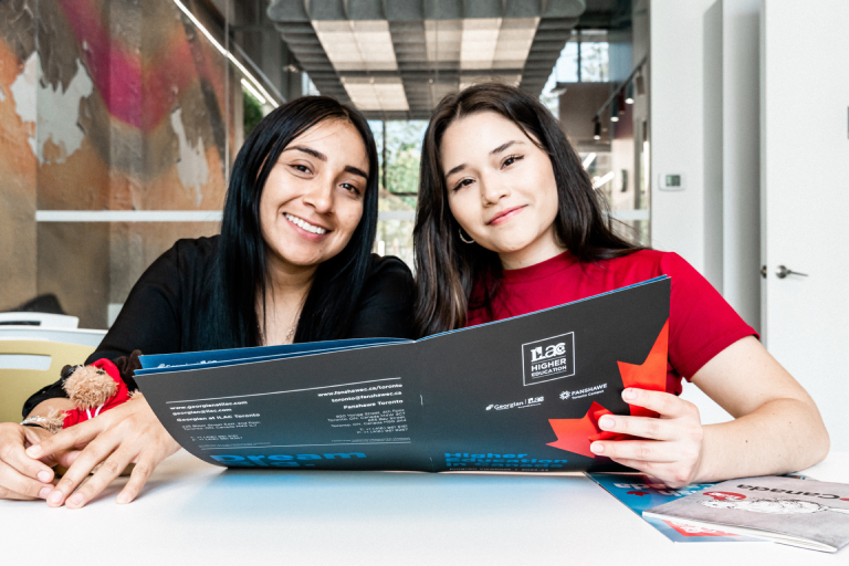 Two international students holding an ILAC brochure